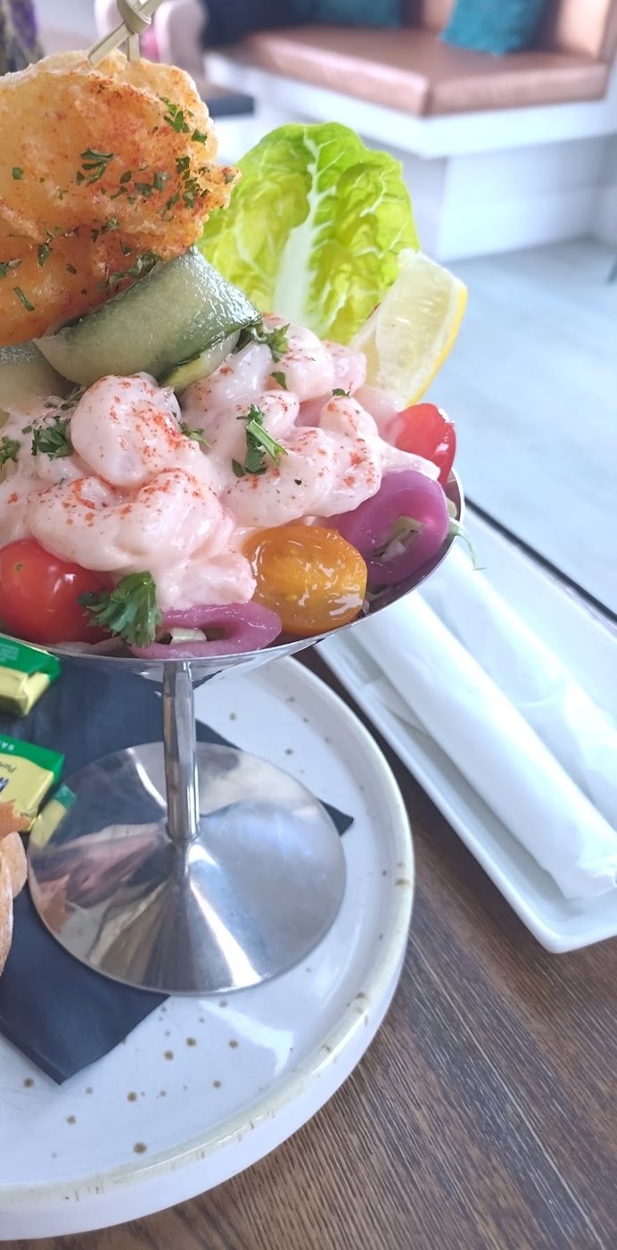 A prawn cocktail in a tall glass with a tempura prawn on top
