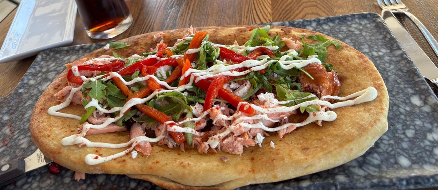 A flatbread topped with peppers, herbs and drizzled sauce