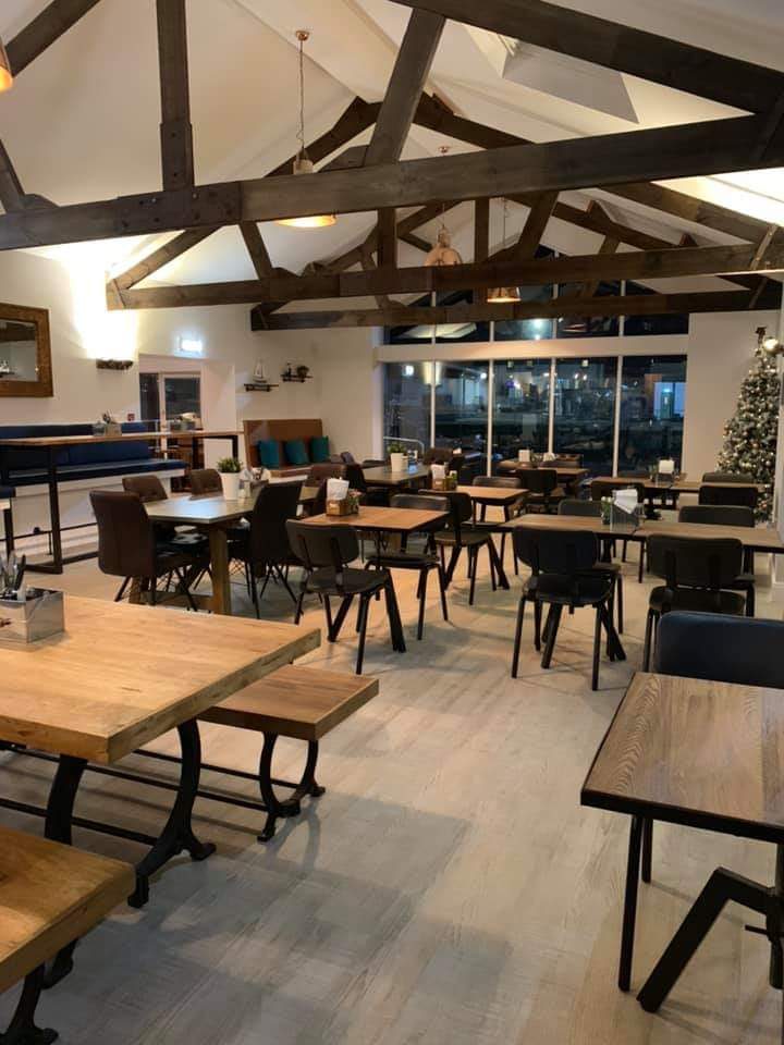 A beamed dining room with wooden tables and big windows